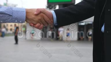 与城市背景模糊的商务握手。 两个商人在城市环境中互相问候。 晃动